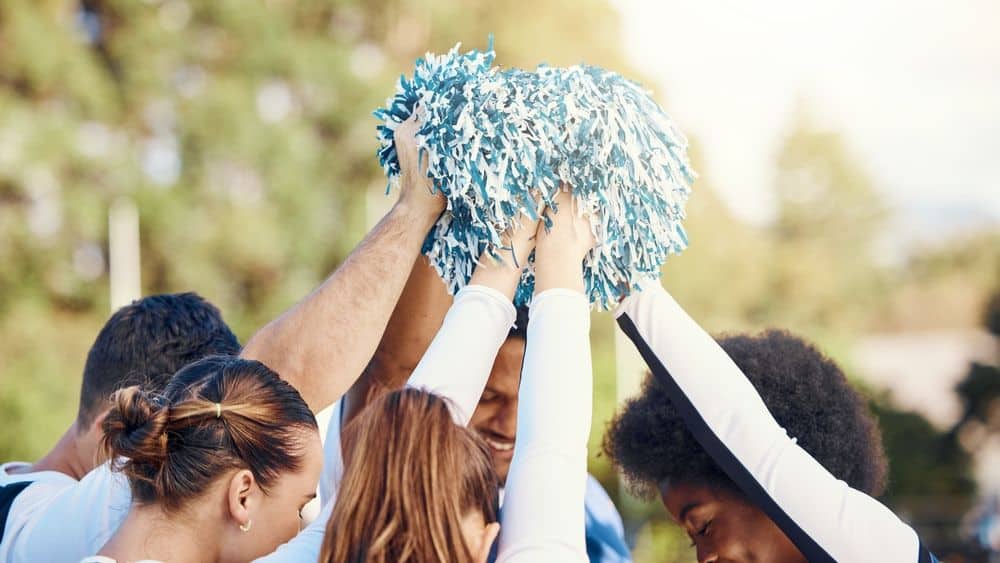 cheer coach and cheerleaders during a motivational huddle