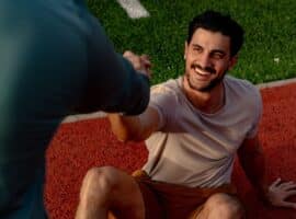 coach helping athlete up after fall on track