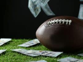 football on turf surrounded by 100 dollar bills