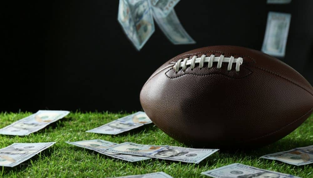 football on turf surrounded by 100 dollar bills