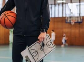 basketball coach holding clipboard on indoor court
