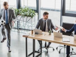 business professional playing with a soccer ball during an office meeting