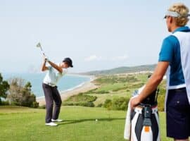 golfer teeing off while caddy observes course strategy.