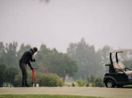 Golf Course Groundskeeper Using Hole Cutter Tool On Foggy Overcast Day