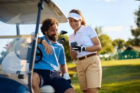 Golfer and Assistant Smiling Together Next to Cart.