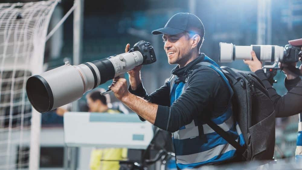 sports photographer capturing live game action with a professional telephoto lens