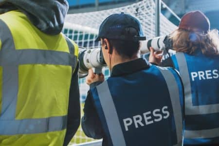 credentialed press photographers shooting sports action from the field level