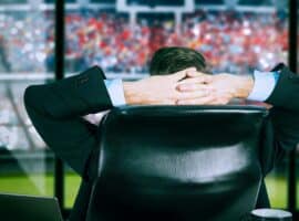 sports executive overlooking a stadium from an office during game day.