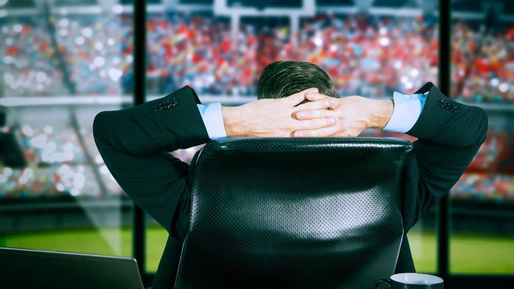 sports executive overlooking a stadium from an office during game day.